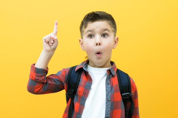 Child boy in glasses on yellow paper wall Great idea Happy smiling schoolboy goes back to school Success motivation winner genius concept