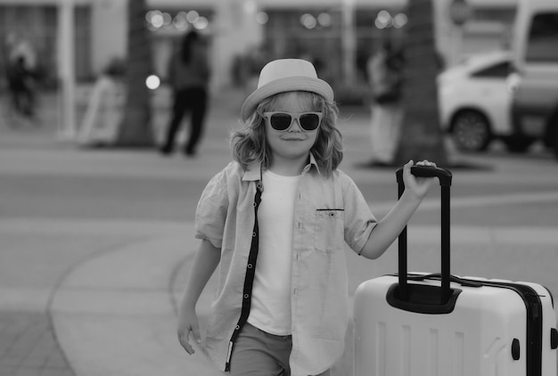 Child boy going on summer trip holding luggage travel bag outdoor