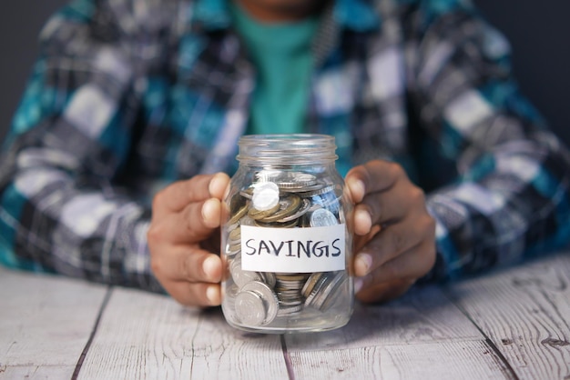 Child boy hand hold a saving coins jar