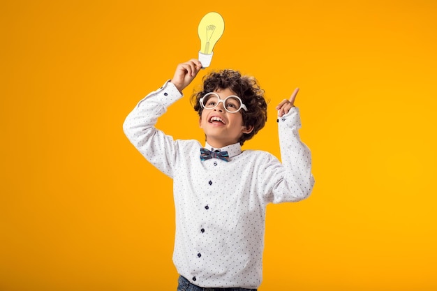 Photo child boy holding paper bulb success motivation winner genius idea concept