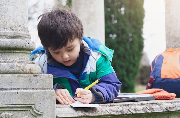 아이 소년 펜을 잡고 숲으로가는 길에 찾은 것에 대해 종이에 쓰거나 그림을 그립니다.