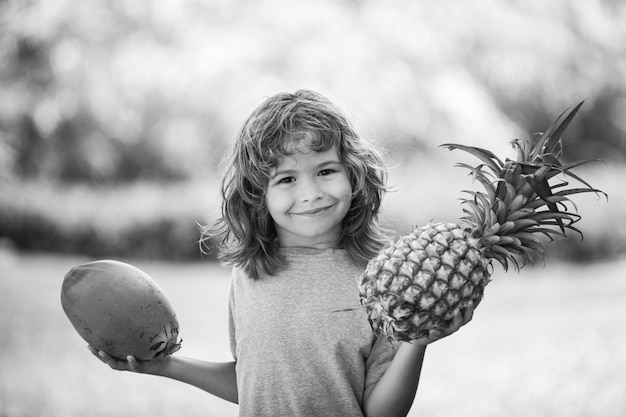 Child boy holding pineapple and coconut smiling with happy face summer fruits