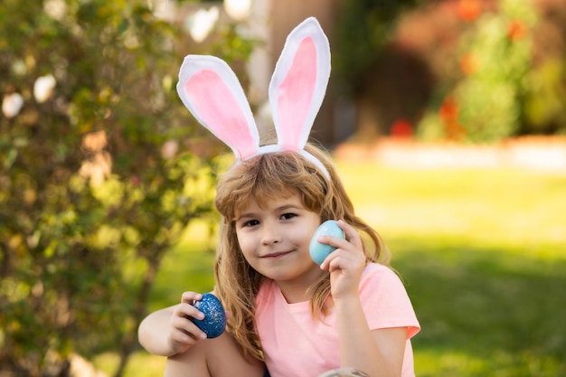 Child boy hunting easter eggs kid with easter eggs and bunny ears outdoor spring holidays