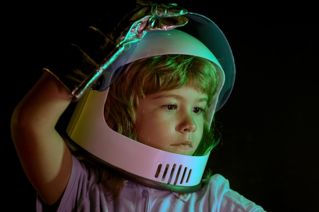 子供の男の子は、自分が宇宙服を着た宇宙飛行士であると想像しています。