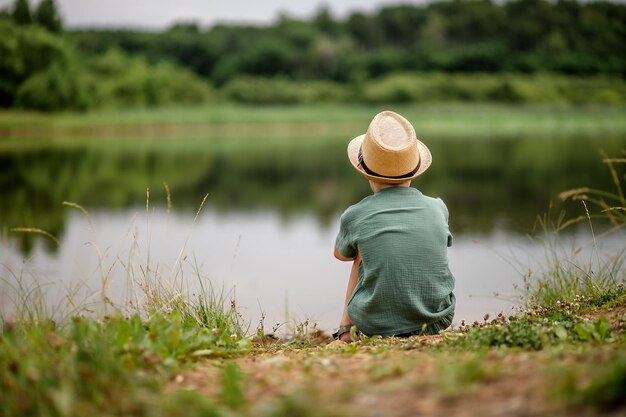 写真 湖の岸に座っている小学生の男の子