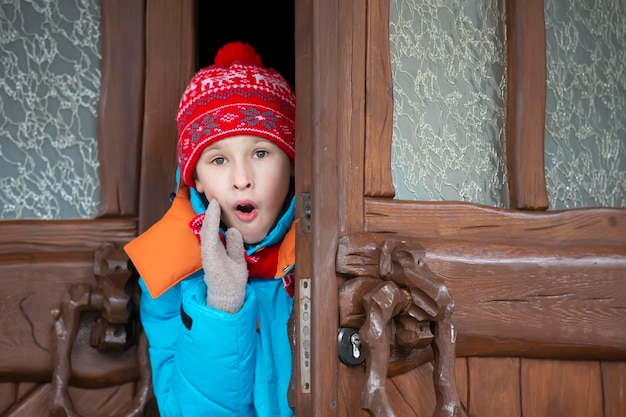 Child boy peeks out the door surprised Winter holidays time