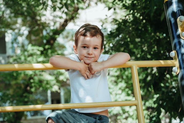 child boy playing and climbing on horizontal bars on the playground in summer