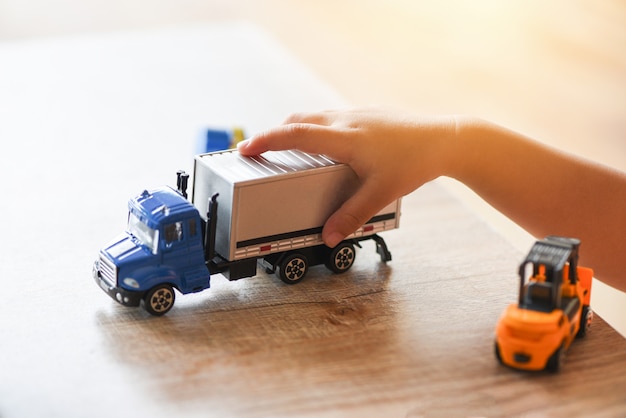 child boy playing toys on table at home - kid hands playing toy car truck