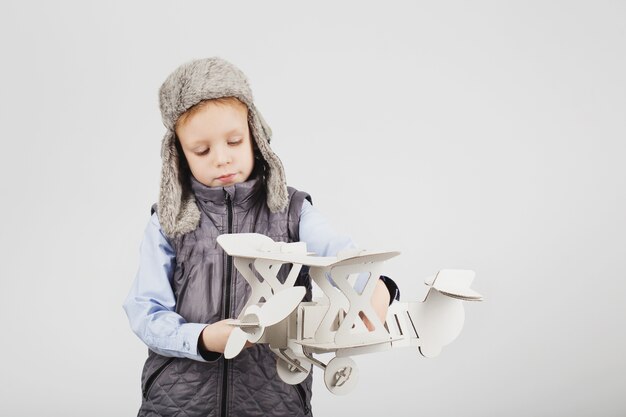 Child boy playing with paper toy airplane and dreaming of becoming a pilot