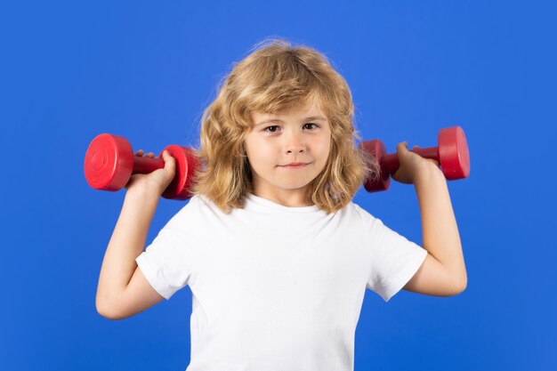 Child boy pumping up biceps muscles with dumbbell Fitness kids with dumbbells