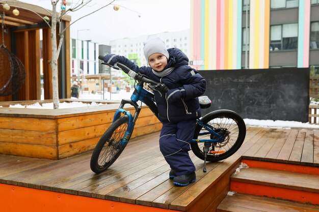 Photo child boy riding a bike in winter