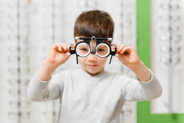 Child boy showing trial frame in ophthalmology clinic, selective focus