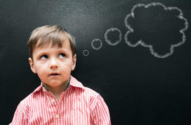 Foto bambino e ragazzo che pensa con una bolla di pensiero sulla lavagna per il disegno e l'illustrazione di idee creative in classe studente bambino e viso con sogni ad occhi aperti contemplando e chiedendo con la lavagna