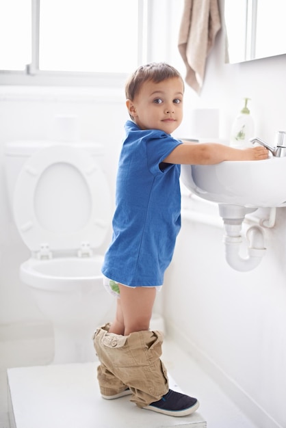 Photo child boy and washing hands in portrait hygiene and prevention of germs or bacteria in bathroom male person kid and crazy humor or funny joke while potty training cleaning and sanitary care