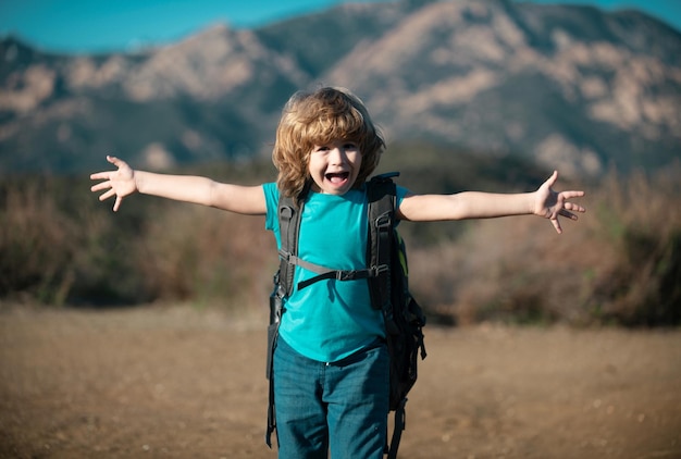 Child boy with backpack hiking in scenic mountains kid local tourist goes on a local hike