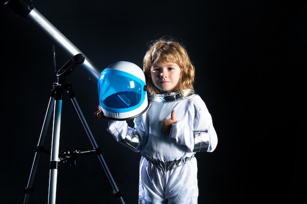 Foto il bambino con un telescopio è vestito con un costume da astronauta concetto di astronomia e astrologia