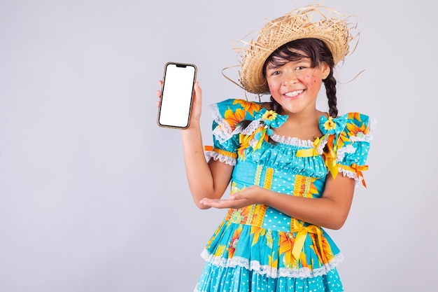 Child brazilian girl with festa junina clothes showing smartphone screen