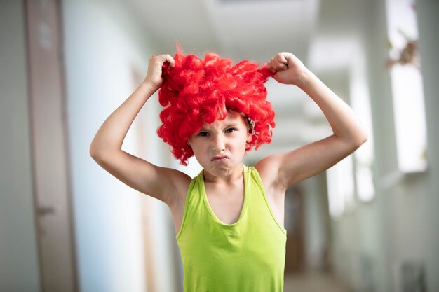 A child in a bright wig Funny boy with red artificial hair Do not like the hairstyle