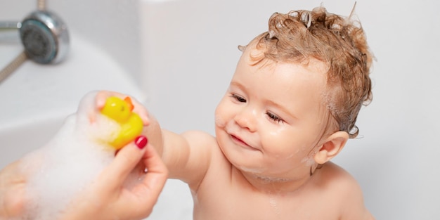 Child bubble bath funny baby kid bathed in foam and washing in bathtub at home