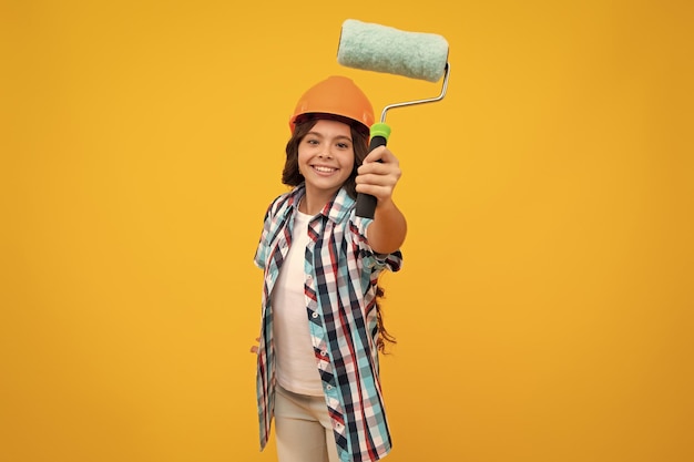 Child builder in hard hat helmet teenage girl painter with painting brush tool or paint roller