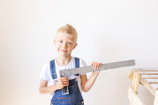 Child Builder measures a white wall with a construction ruler, construction and repair concept