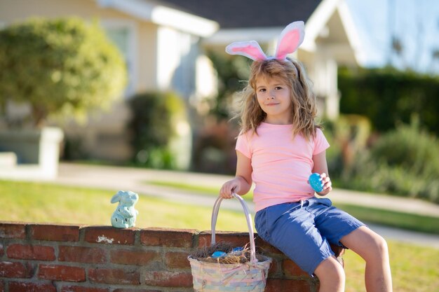 Child in bunny ears hold Easter egg Boy hunting easter egg Easter holiday Boy in rabbit costume play outdoors