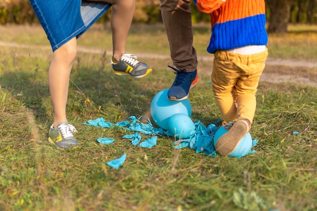 子供は両親と一緒に歩いている間、楽しんで風船を破裂させます。