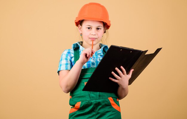 Child care development foreman inspector repair safety expert future profession small girl repairing in workshop builder engineer architect kid worker in hard hat examining