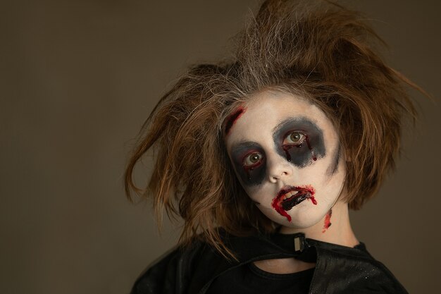 Photo a child in a carnival costume with a scary face painting on halloween