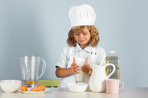 Child chef cook prepares food on isolated grey studio background kids cooking teen boy with apron an