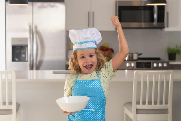 Child chef cook with cooking plate Kid chef cook wearing cooker uniform and chef hat preparing food on kitchen Cooking culinary and kids food concept
