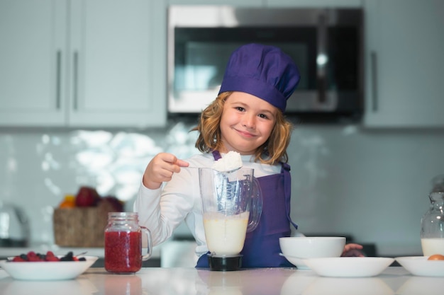 Child chef cooking meal chef kid boy in apron and chef hat cooking at kitchen healthy food