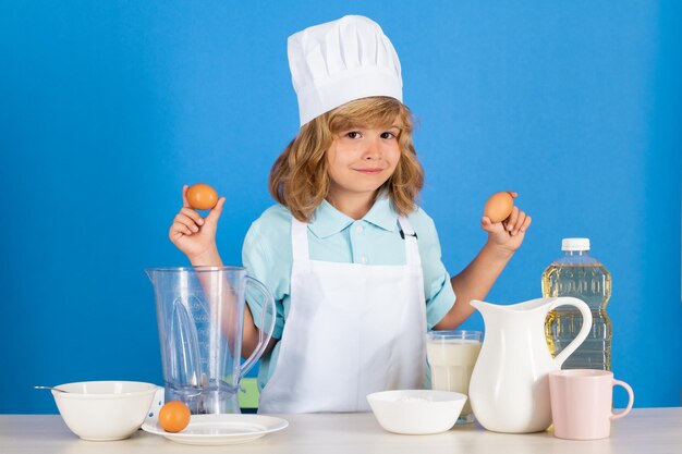 Photo child chef hold eggs dressed cook baker apron and chef hat isolated on studio background healthy nut