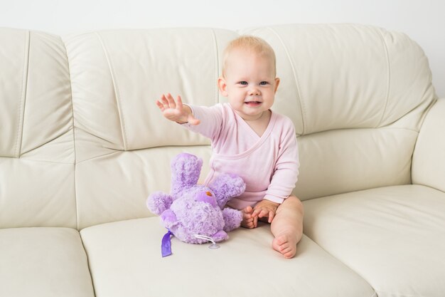 子供、子供時代、子供たちのコンセプト-ソファの上の魅力的な女の赤ちゃんの肖像画