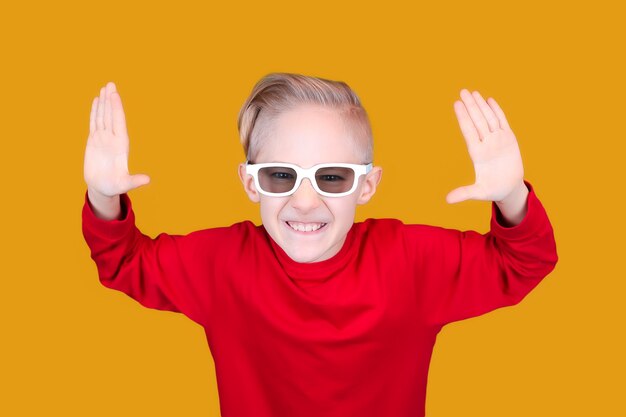 A child in children's 3D glasses joyfully raises his hands