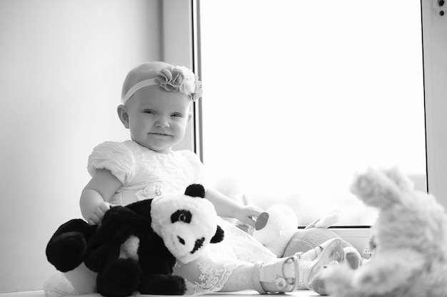 Child in the children's room. The kid is sitting on the windowsill at the window. Happy child with toys.