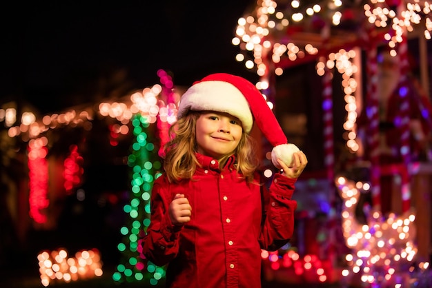 Ребенок на рождественском украшении перед ночным домом рождественским вечером на фоне n