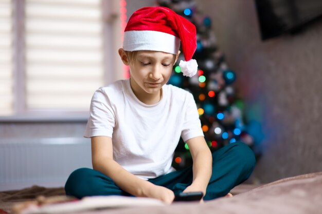 a child in a Christmas Santa hat on the background of a garland