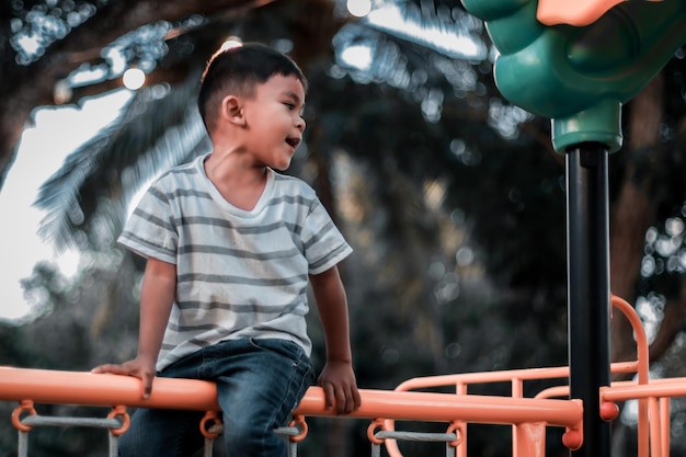 한 어린이가 더운 여름날 놀이터에 있는 공원의 고산 격자를 등반합니다. 어린이를 위한 공원 엔터테인먼트 및 레크리에이션