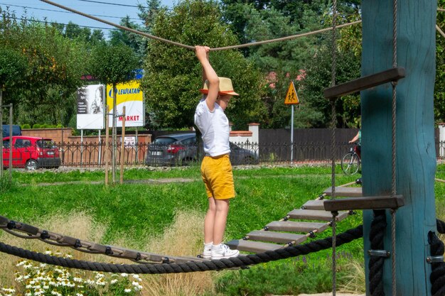 Foto un bambino si arrampica su una griglia alpina in un parco su un parco giochi in una calda giornata estiva