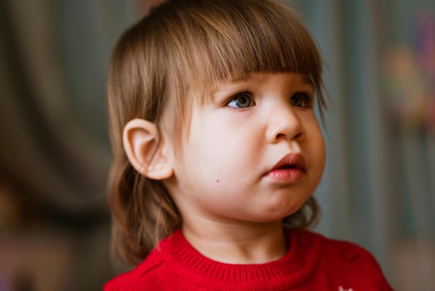 Photo child close-up portrait of little girl in red sweater waiting to receive