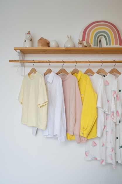 Child clothes hanging on a wooden hanger against a white wall