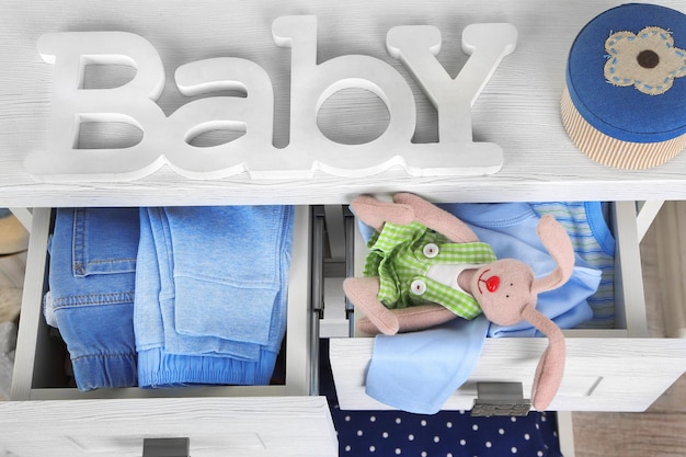 Child clothes in wooden chest of drawer close up