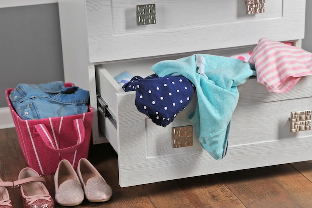 Photo child clothes in wooden chest of drawer close up