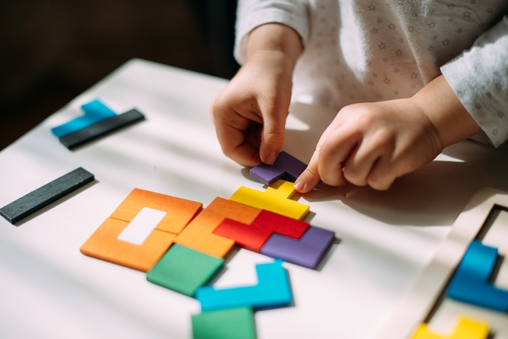 Photo child connects pieces of colored wooden puzzle.