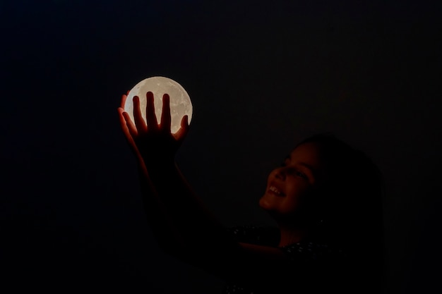 Child contemplating the moon in hands