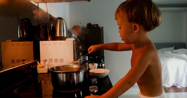 Child cooks himself pasta in the kitchen in the morning