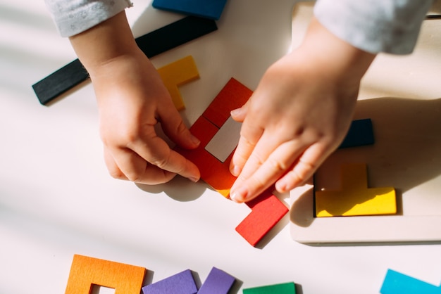 Il bambino crea una figura da un puzzle colorato sul tavolo.