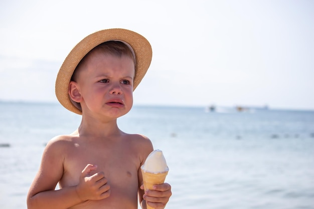 The child cries and eats ice cream on the beach