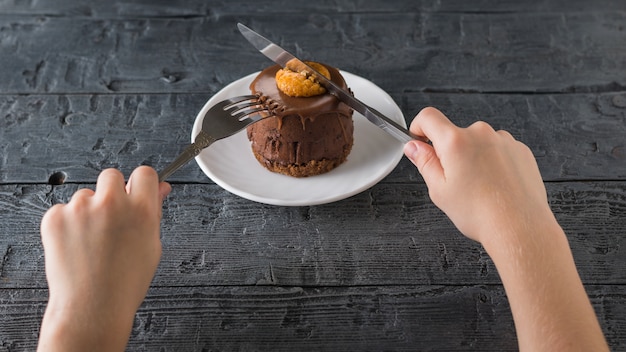 The child cuts a fresh dessert with a knife in a white Cup on a wooden table